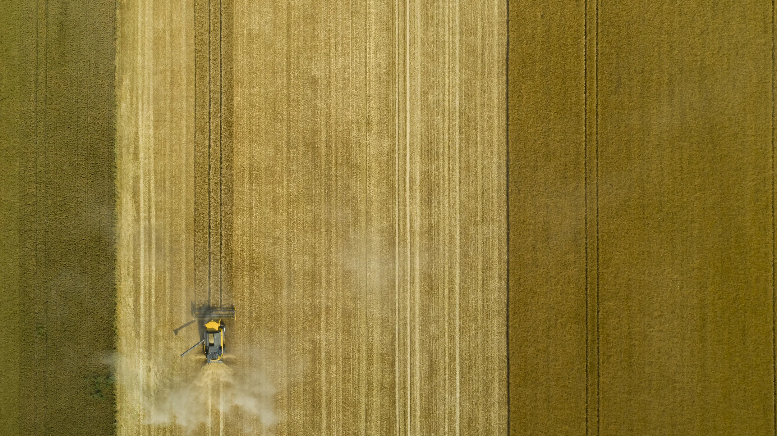 Vue verticale d’une machine agricole dans un champ aux bandes parallèles.