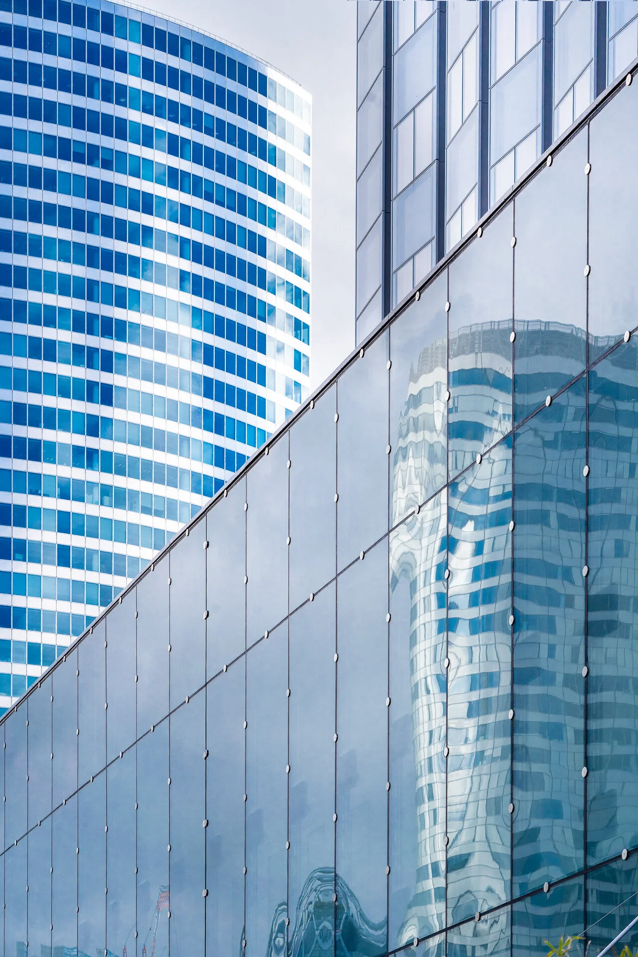 Tour vitrée et son reflet déformé dans la façade d’un bâtiment voisin à La Défense.