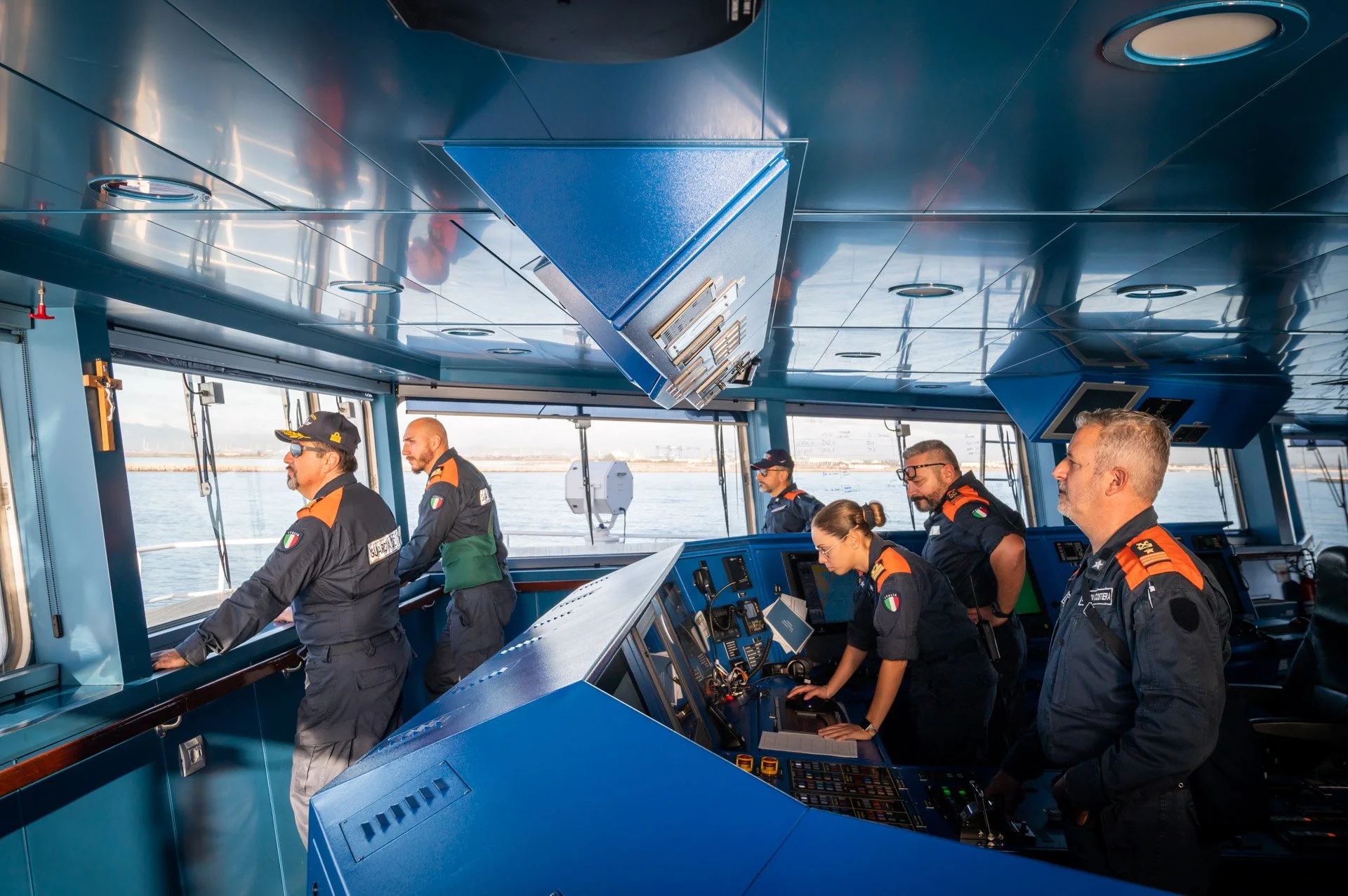 Vue d'ensemble et détails de la passerelle d'un navire, montrant un équipage en uniforme travaillant aux postes de commande et les équipements techniques du pont.