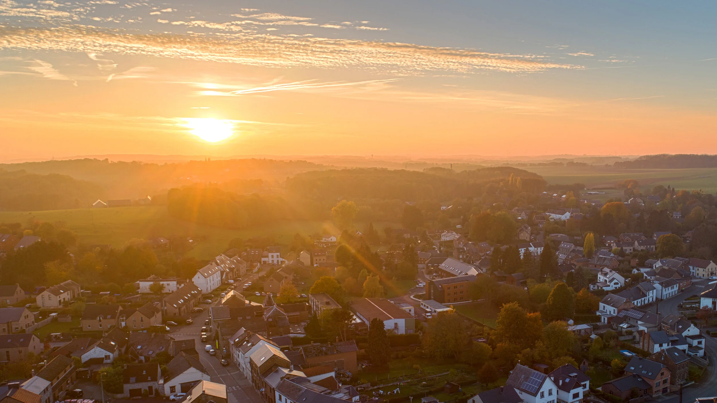 Vue aérienne d’un village et de ses toits au coucher du soleil.