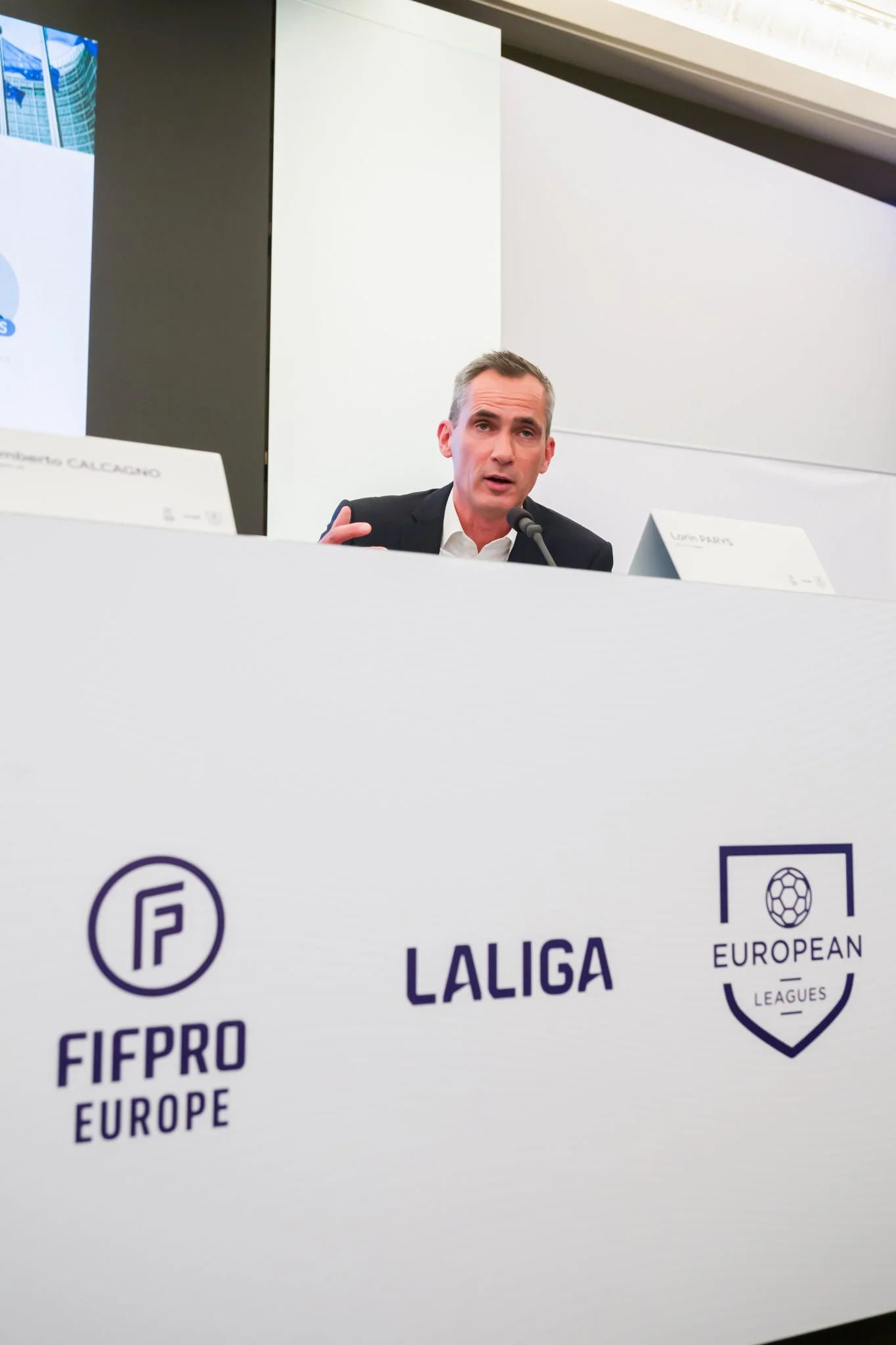 La conférence de presse de LALIGA. Un homme parlant lors d'une conférence, avec les logos de FIFPRO Europe, LaLiga, et European Leagues visibles sur un panneau.
