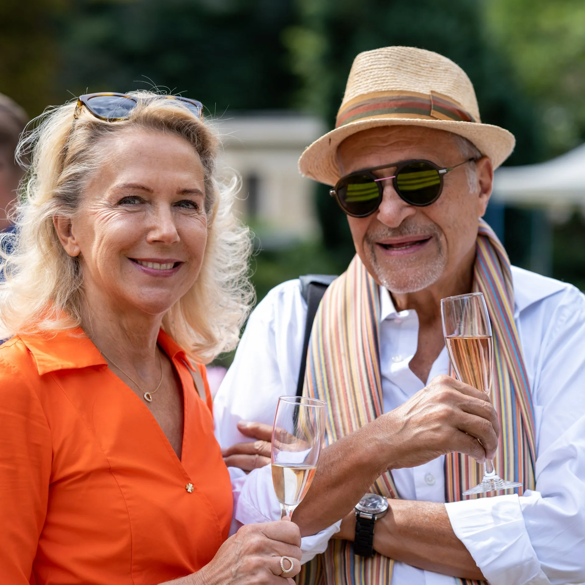 Jean Boghossian, portant un chapeau et des lunettes de soleil, échange avec une participante lors de la Summer Party à la Villa Empain.