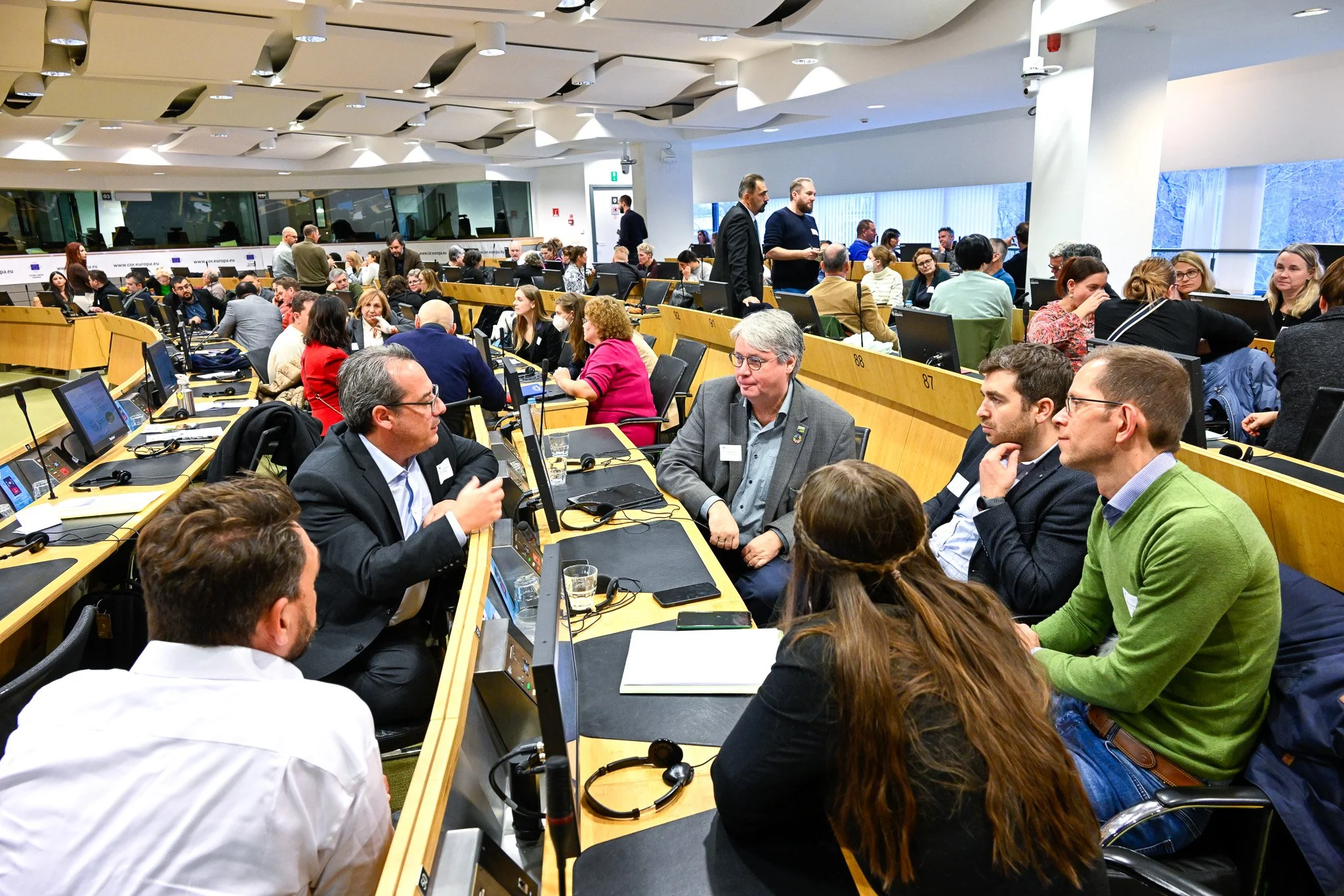 une conférence dans le quartier européen à Bruxelles. Groupe de personnes discutant dans une salle de conférence moderne, avec des ordinateurs devant eux.