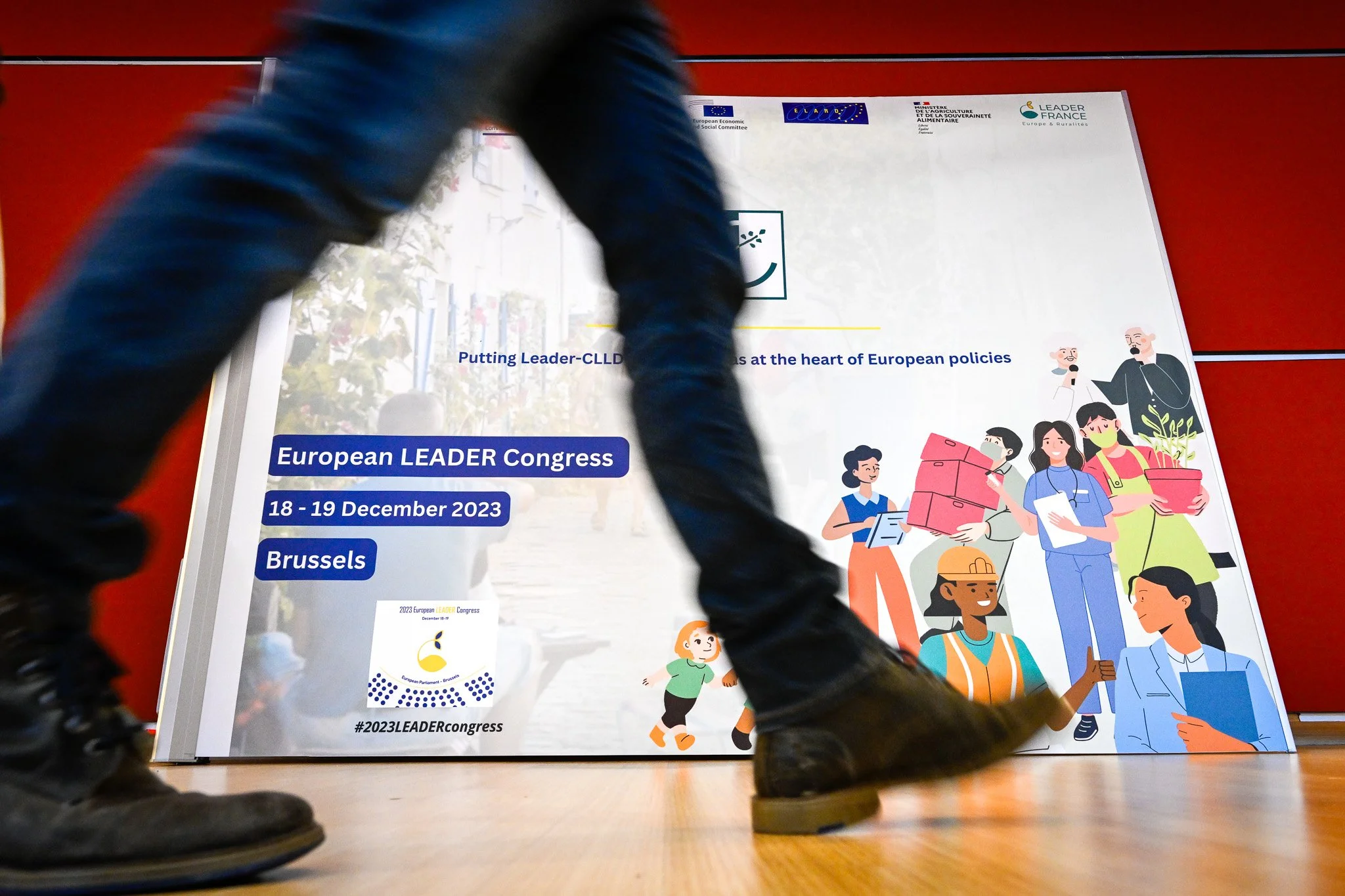 Une personne passe devant l’affiche du Congrès européen LEADER, organisé à Bruxelles les 18 et 19 décembre 2023.