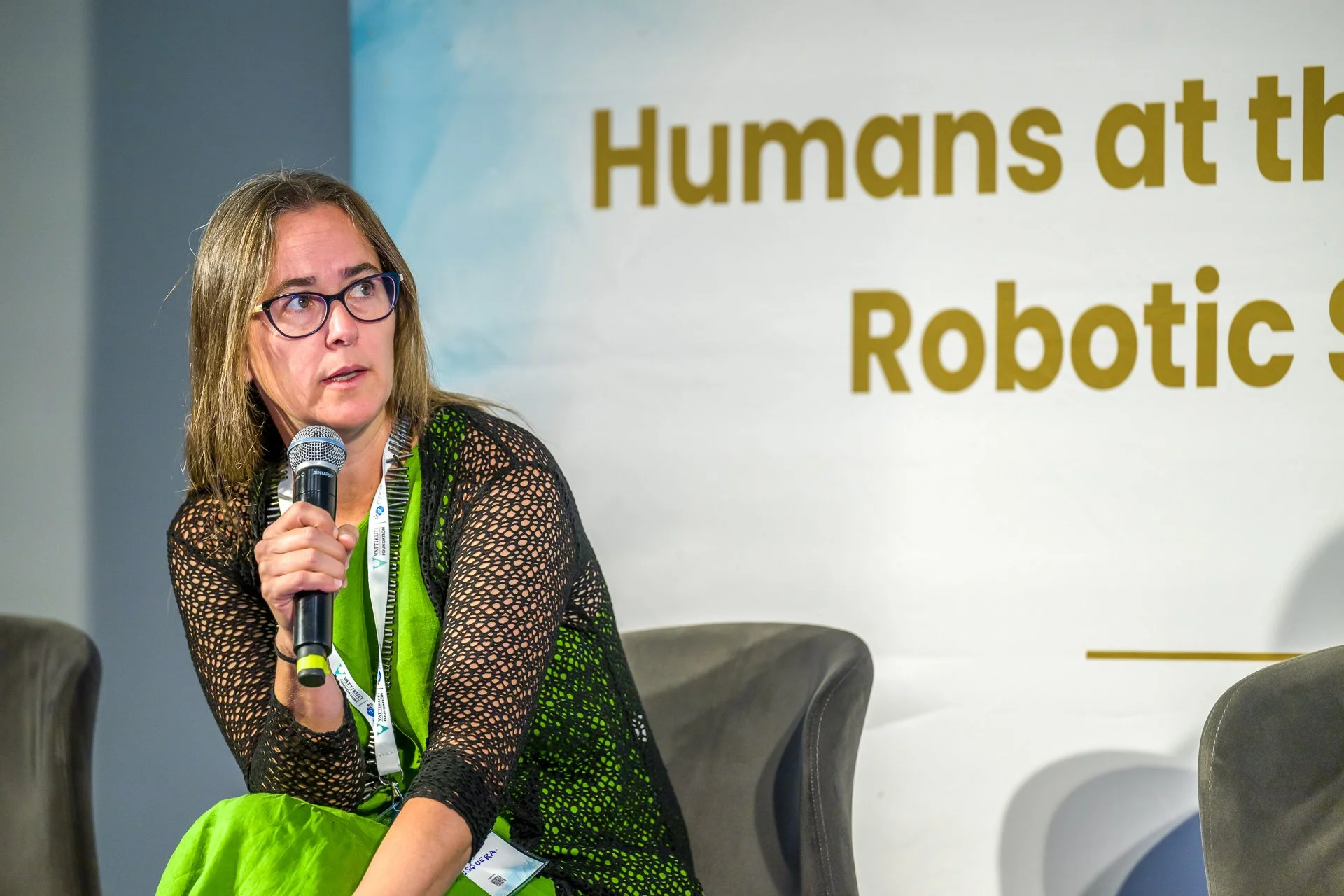 Une intervenante assise prend la parole au micro lors de la conférence « Humans at the Robotic Summit ».