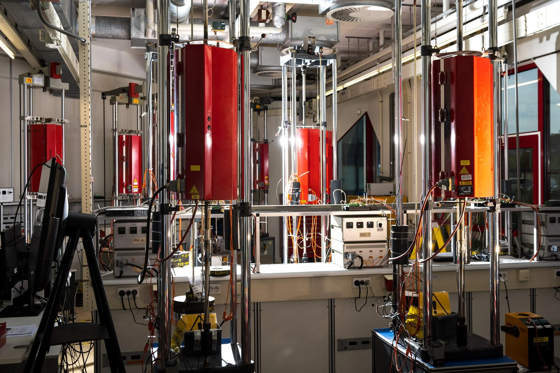 Installation de laboratoire composée de structures métalliques, de grands éléments rouges et de câbles électriques.