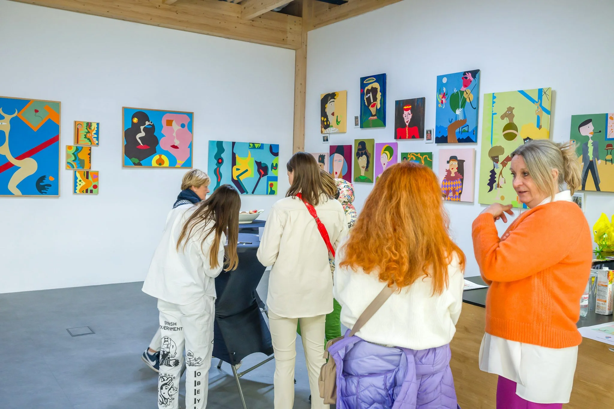 Visiteurs observant des peintures colorées accrochées aux murs d'une galerie d'art.